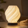 Decorative table lamp with wavy design on a wooden surface, blurred background